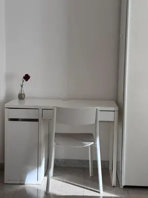 a white desk with a chair and a vase with a flower at Metronio Relax in Rome