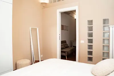 a bedroom with a bed and a chair and a mirror at Domina Apartments Roma - San Pietro 3 in Rome