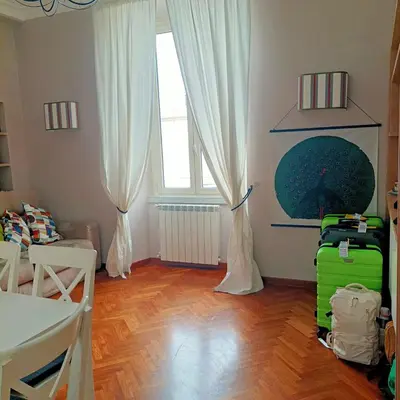 a living room with a green suitcase and curtains at Colosseo Elegant Apartment in Rome