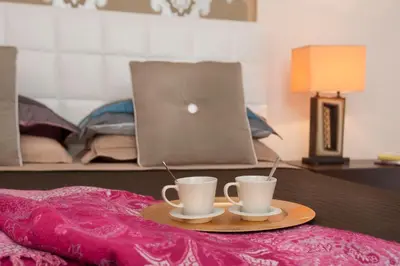 two coffee cups on a tray on a bed with a laptop at La Maison de Kappa in Rome