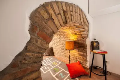 a room with a brick wall with a bed and a lamp at La Maison de Kappa in Rome