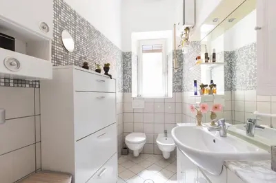 a white bathroom with a sink and a toilet at Cozy and Bright Pyramid Apartment in Rome