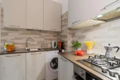 a kitchen with white cabinets and a washing machine at Cozy and Bright Pyramid Apartment in Rome