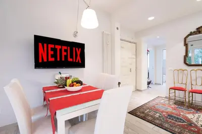 a white dining room with a red table and chairs at Vatican City Historic Center -Luxury Flat with Garden and Private Parking in Rome