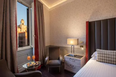 a hotel room with a bed and a chair and a window at The Inn at the Spanish Steps Elegant Collection - The Gem in Rome