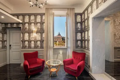a living room with two red chairs and a window at The Inn at the Spanish Steps Elegant Collection - The Gem in Rome