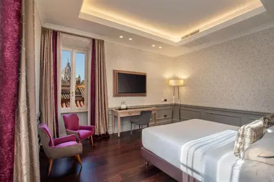 a hotel room with a bed and a desk at The Inn at the Spanish Steps Elegant Collection - The Gem in Rome