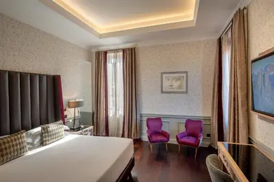 a bedroom with a bed and two purple chairs at The Inn at the Spanish Steps Elegant Collection - The Gem in Rome