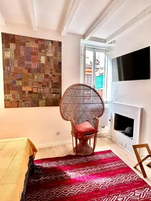 a wicker chair sitting in a room with a fireplace at Colosseo Lovely studio apartment in Rome