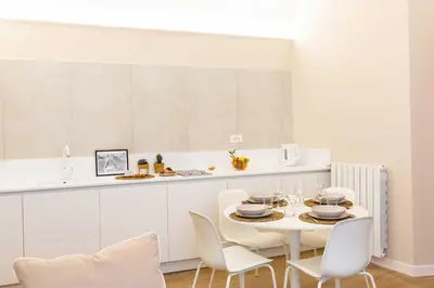 a white kitchen with a white table and chairs at Monti Nonna Francesca - ZENO 49 in Rome