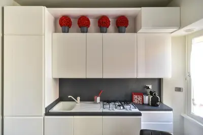 a kitchen with white cabinets and red flowers on top at Lata Luxury Apartment in Rome