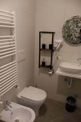 a white bathroom with a toilet and a sink at COLOSS IMPERIAL SUITE Guest House in Rome