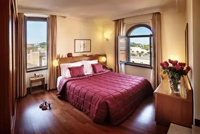 a bedroom with a bed with a red bedspread and two windows at Hotel Ponte Sisto in Rome