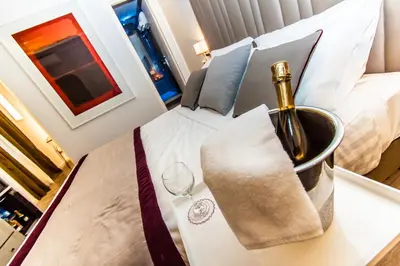 a bottle of champagne and a wine glass on a bed at Calisto Luxury Trastevere in Rome