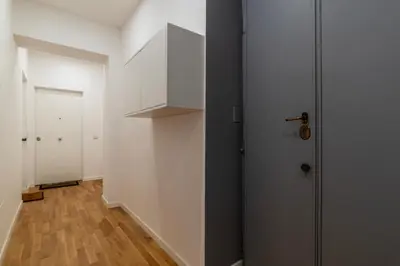 a hallway with white walls and a door and a wooden floor at Bartolomeo de' Vaccinari - FromHometoRome in Rome