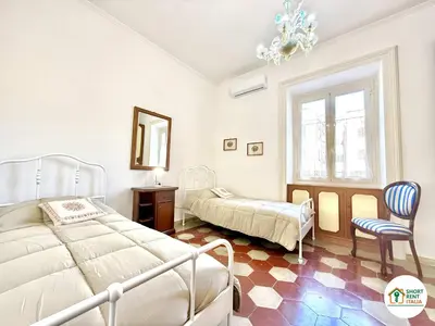 a bedroom with two beds and a chair and a chandelier at Santa Maria Maggiore - Vittorio Emanuele House in Rome