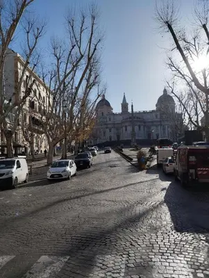 a cobblestone street with cars parked in front of a building at La casetta ai fori imperiali in Rome