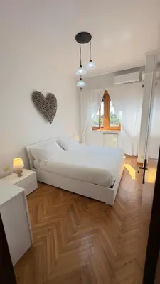 a bedroom with a white bed and a wooden floor at La Camilla in Rome