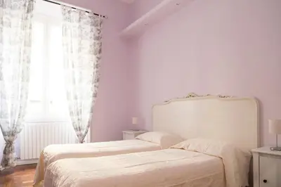 a white bedroom with two beds and a window at Arcudi Romance Home in Rome