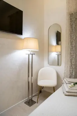 a bedroom with a lamp and a chair and a mirror at Enjoy Colosseum Apartment in Rome