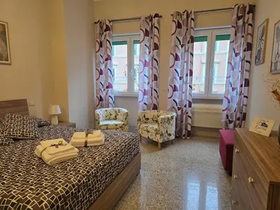 a bedroom with a bed and two chairs and windows at Ritiro Romano in Rome