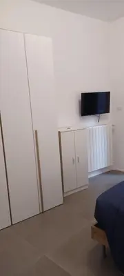 a bedroom with white cabinets and a flat screen tv at Alloggio Turistico A casa di Anna in Rome