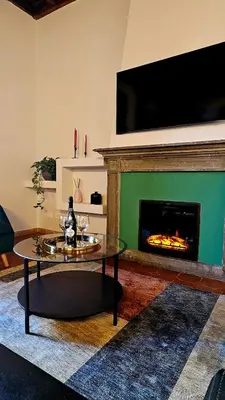 a living room with a fireplace with a tv and a table at Mica Aurea Apartments Trastevere in Rome
