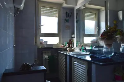 a bathroom with a counter and a sink and two windows at Appartamento Elena's House in Rome