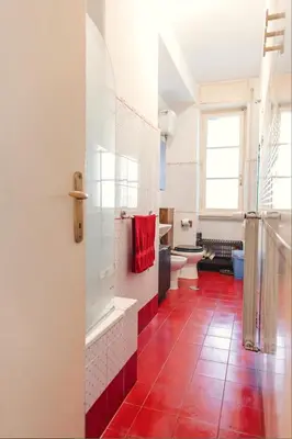 a bathroom with a red tile floor and a toilet at Camera Privata Nomentana per medio lungo periodo in Rome