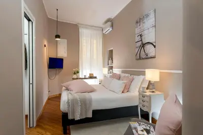 a bedroom with a bed with white sheets and pink pillows at Maisondesfleurs in Rome