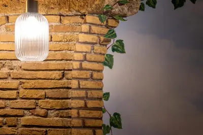 a light hanging from a brick wall with a ivy at iFlat Campo de Fiori's Comfy Gem in Rome