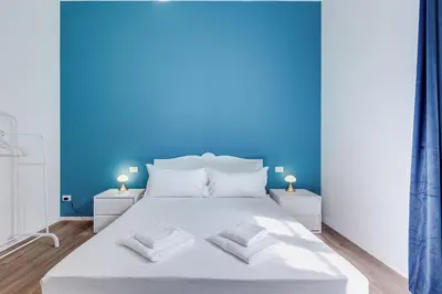 a bedroom with a white bed with blue walls at BMGA l Aurelian 3Bdr 6-Guest Gem in Rome