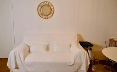 a white couch sitting in a room with a mirror at La Nuova Casa Di Zia - near metro A Ponte Lungo in Rome