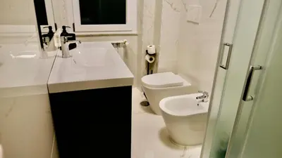 a white bathroom with a sink and a toilet at La Nuova Casa Di Zia - near metro A Ponte Lungo in Rome