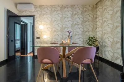 a dining room with a glass table and two pink chairs at Morgana - Charming Apartment Close to Vatican in Rome