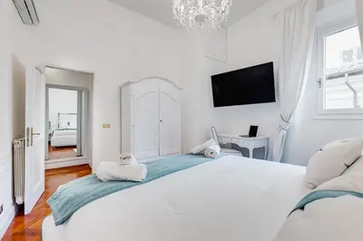a white bedroom with a large bed and a tv at New opening Spagna Suite in Rome