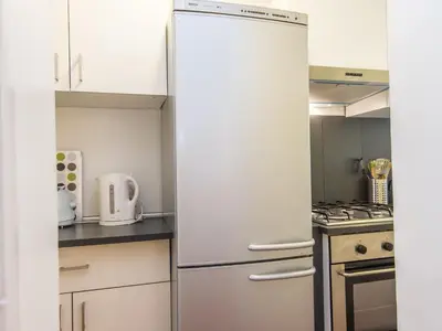 a kitchen with white cabinets and a refrigerator at Spacious 2BR in the historic center in Rome