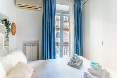 a bedroom with a white bed with blue curtains and towels at iFlat Classy & Spacious apt near Campo de Fiori in Rome