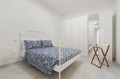 a white bedroom with a white bed with blue sheets at Visconti58 Boutique House - Modern apt with balcony in Rome