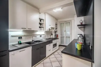 a kitchen with white cabinets and a black counter top at Navona, 3 bedrooms, unique and spectacular view in Rome