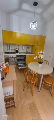 a kitchen with a table and chairs and yellow cabinets at Bijoux de Rome Campo dei Fiori Apart in Rome