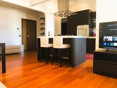 a kitchen with a bar with white chairs and a television at Urbanhome, ready to visit Rome! in Rome