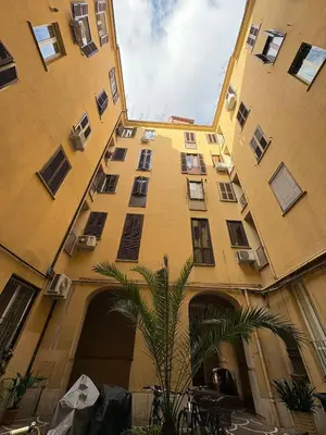 a tall building with a palm tree in front of it at Guest House David San Lorenzo in Rome