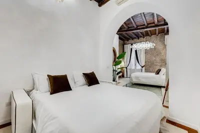 a bedroom with a large white bed and a chair at NEW ROMAN Apartment - Rome Dream Home in Rome