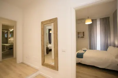 a white bedroom with a mirror and a bed at Thebestinrome Piazza del Popolo - Vico in Rome