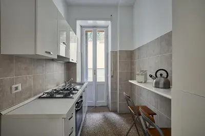 a kitchen with white cabinets and a stove top oven at Domus Erasmo in Rome
