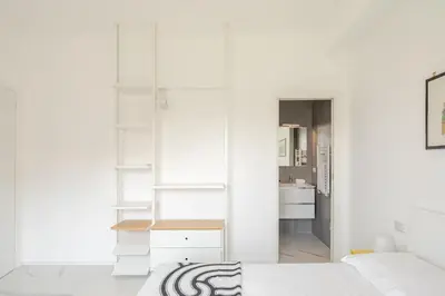 a room with white walls and white furniture and a kitchen at Sunset House - San Paolo in Rome