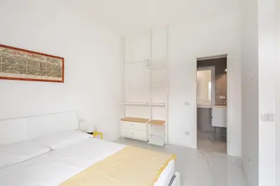 a white bedroom with a bed and a desk at Sunset House - San Paolo in Rome