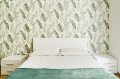 a bedroom with a white bed with a leafy wallpaper at Suite 155 in Rome