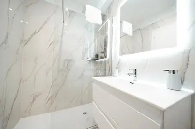 a white bathroom with a sink and a mirror at Apartment in Rione Ludovisi in Rome